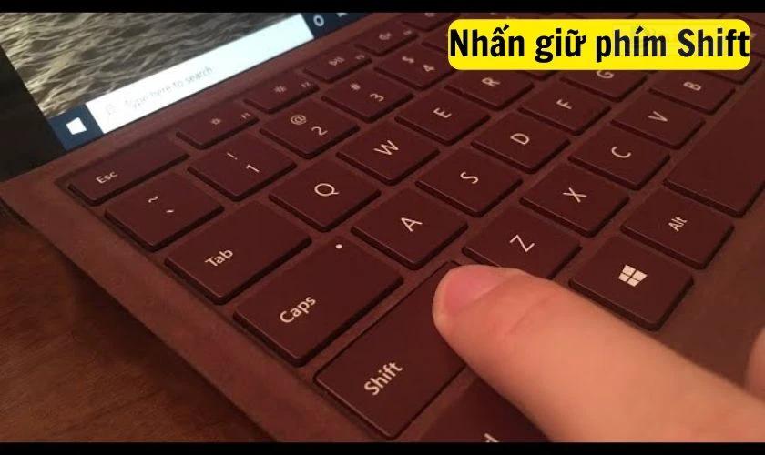 Nhấn và giữ phím Shift ngay khi MacBook bắt đầu khởi động